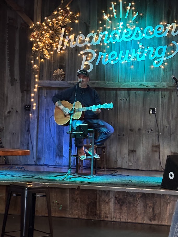 Roger Avery Jr. performing with acoustic guitar